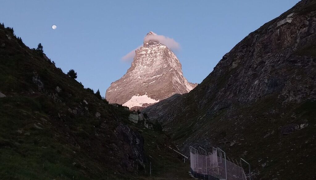 view on the matterhorn while the sun is setting and an almost full moon, close to zermatt, switzerland